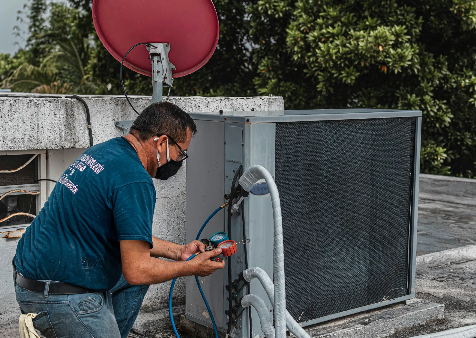 Technician servicing an air conditioning unit on a rooftop.